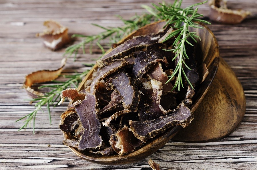 jerked meat, cow, deer, wild beast or biltong in wooden bowls on a rustic table